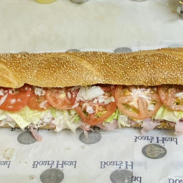 A long sub sandwich is sitting on top of a piece of paper.