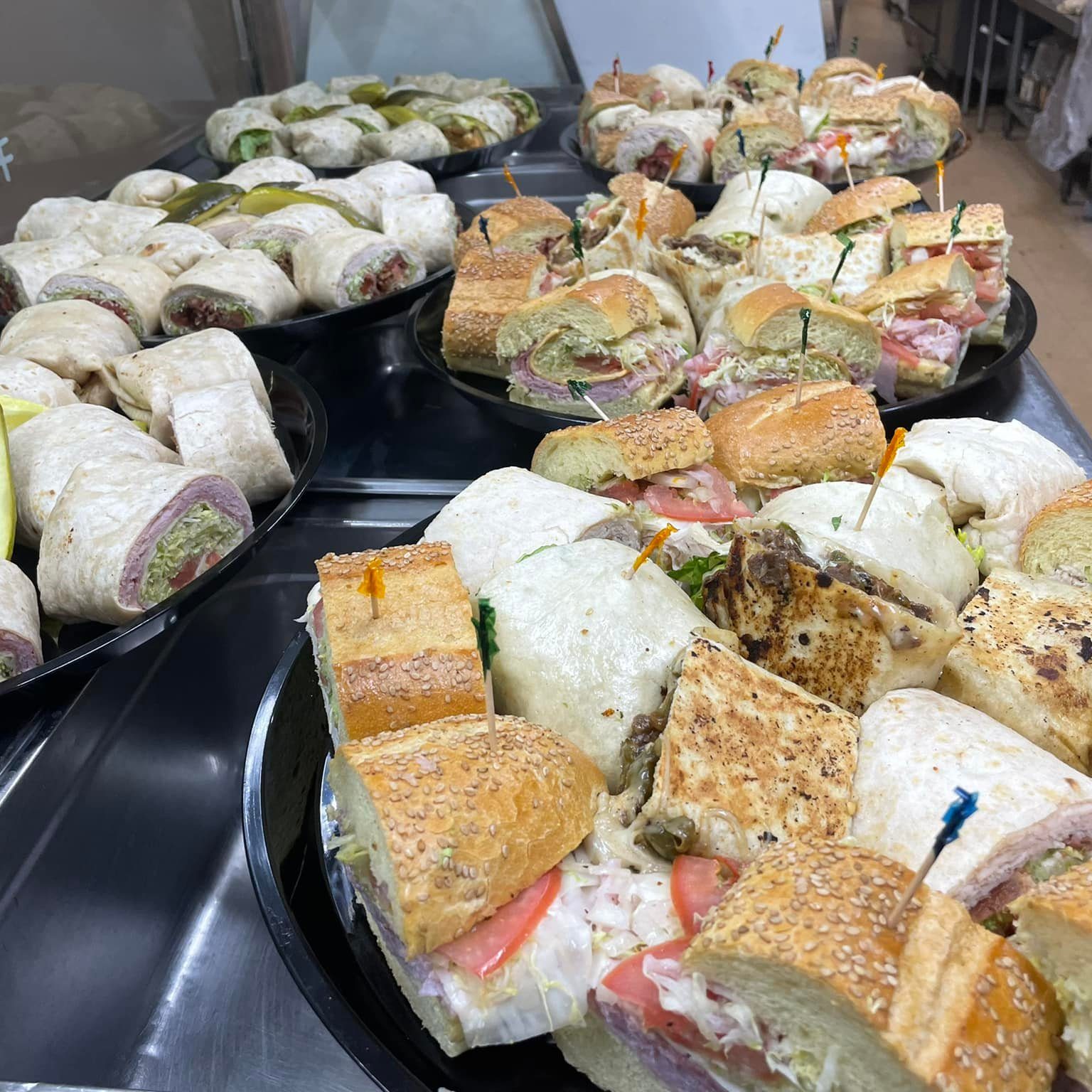 A variety of sandwiches are on display at a buffet.