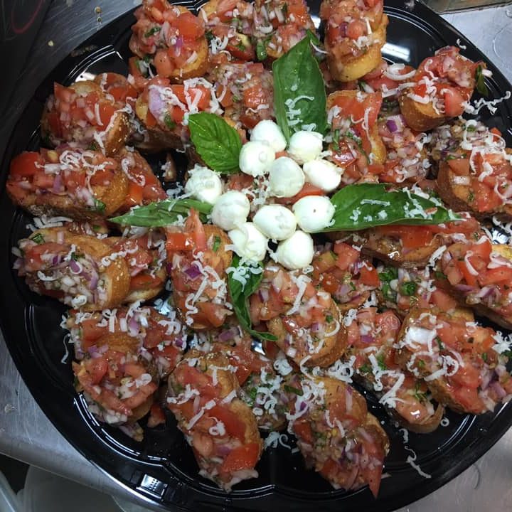 A plate of appetizers with tomatoes and basil on it.